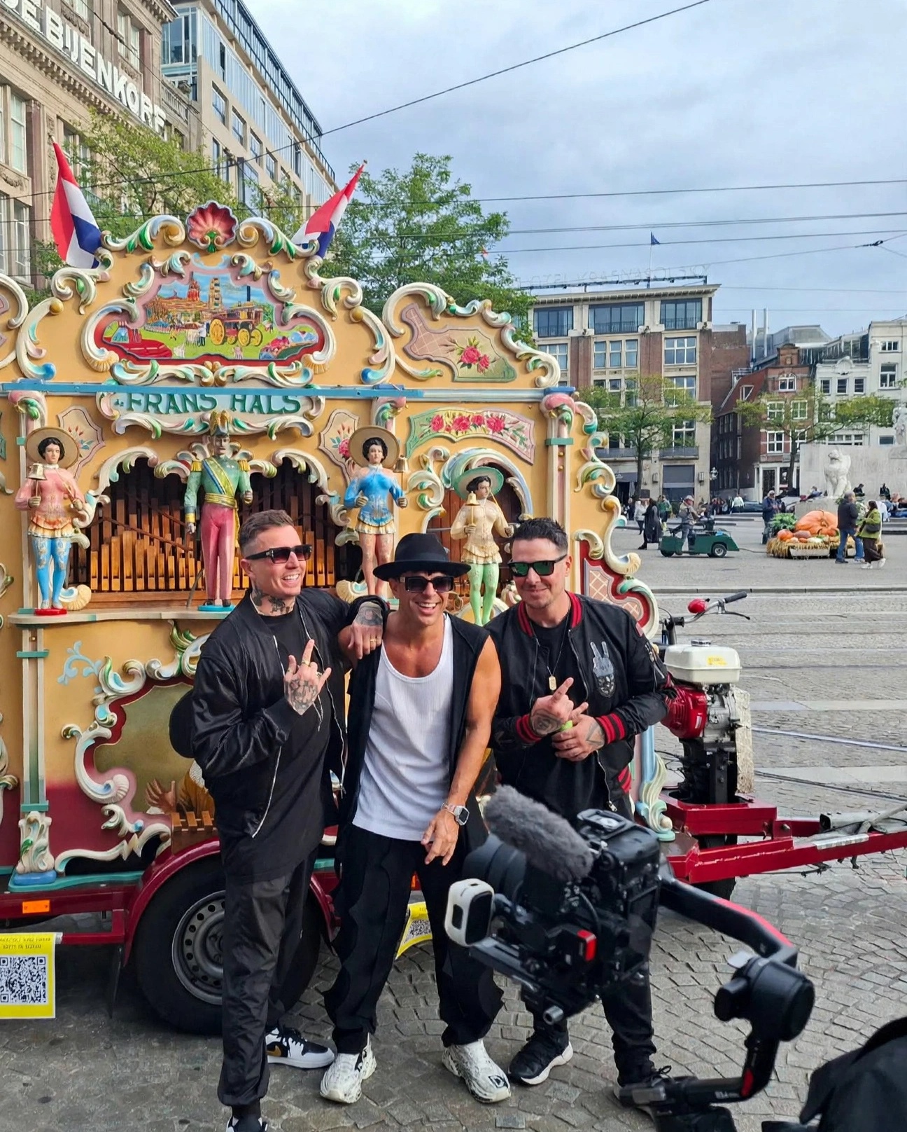 Three men posing beside a colourful Dutch fairground attraction in Amsterdam